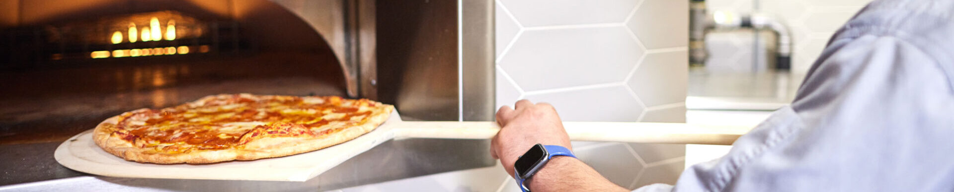 chef removing pizza from oven