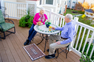 Two senior residents at Croasdaile Village enjoying a cup of coffee together on an outdoor porch.