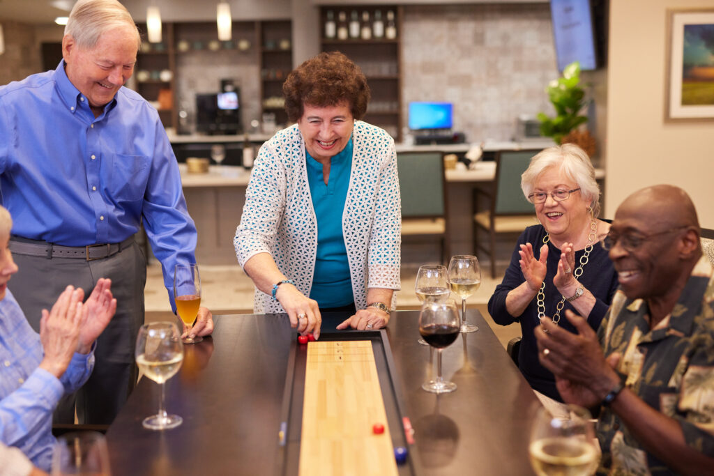 Seniors playing a game over glasses of wine at Croasdaile Village