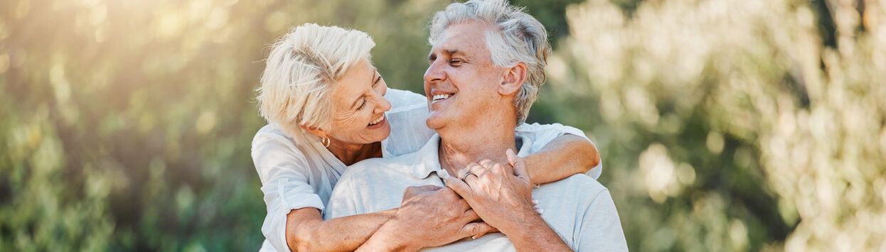 Happy couple senior and hug on park bench for love support and bonding together in retirement and nature garden Smile relax and elderly woman embrace man in Australia backyard for marriage trust