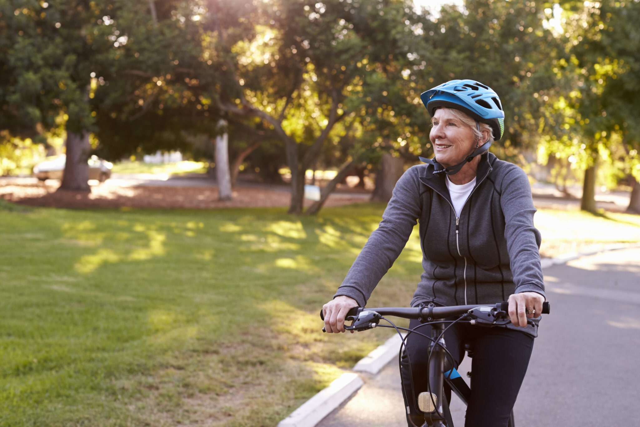 Elderly woman biking along a path